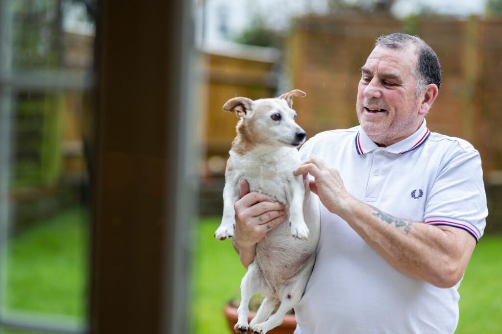 Elderly Man in Polo Shirt Holding Dog in Hands