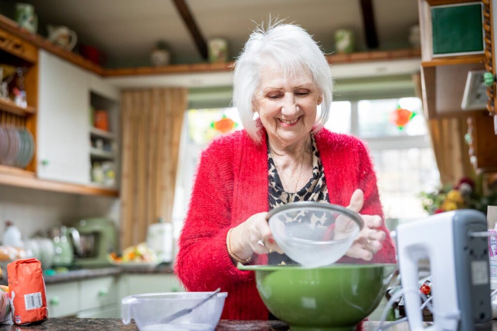 Elderly Woman Sifting Flour in Kitchen
